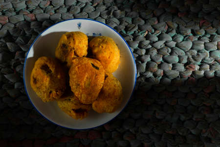 Aloo bonda in a plate on a matte background with artistic lighting