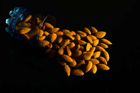 Badam nuts in a glass spread out on a dark backgroundの写真素材