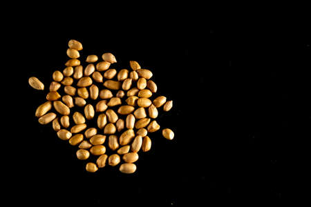 Fresh and raw Peanuts spread out on a dark table