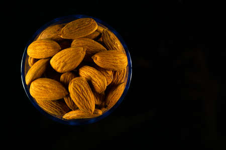 Protein-rich Raw Badam stacked in a glass on a dark tableの写真素材