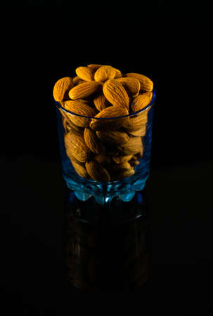 Protein-rich Raw Badam stacked in a glass on a dark tableの写真素材