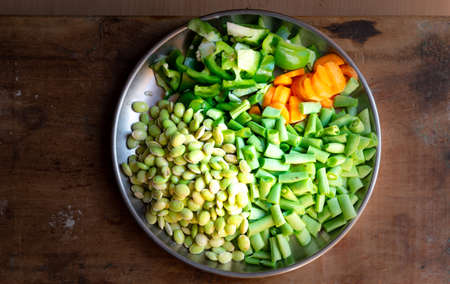 Fresh vegetable cut pieces in a plate on a wooden background