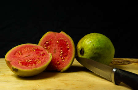 Guava fruit cut into pieces and kept on the table alongside a full guava fruitの写真素材