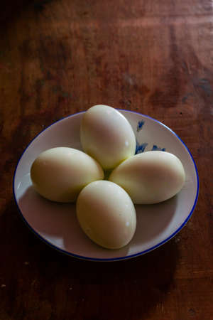 Four boiled eggs in a plate kept on a wooden tableの写真素材