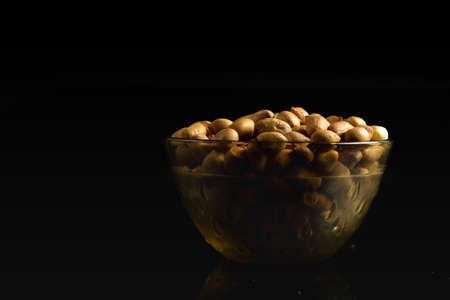 Raw groundnut in a bowl placed on a dark backgroundの写真素材