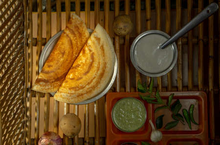 Homemade delicious and tasty dosa with selective focus and lighting on a cane backgroundの写真素材