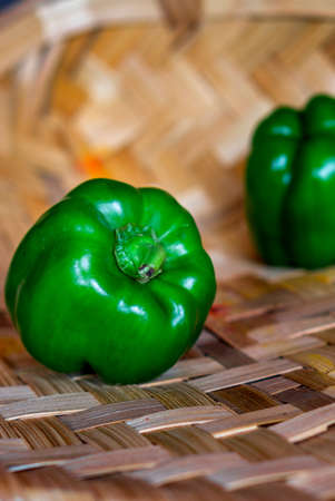 Fresh green capsicum vegetable placed on a bamboo backgroundの写真素材