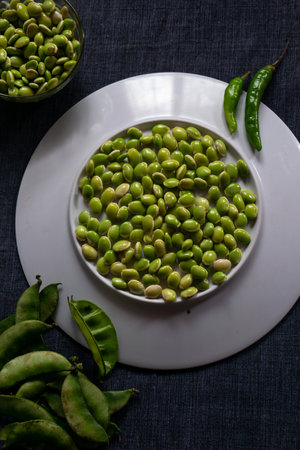 Fresh green lima beans stacked together on a white plate with selective focusの写真素材