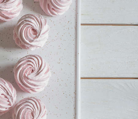 pink homemade marshmallow (zephyr) lies on a white plate on a wooden table. Top viewの写真素材