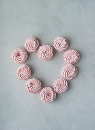Merengue Marshmallow Zephyr lined in a heart shape on a white background. Flat lay. Top view. Pink...