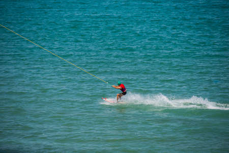 Wakeboarding. Fit attractive wakeboarder looking straight ahead while riding over the surface of waterの写真素材