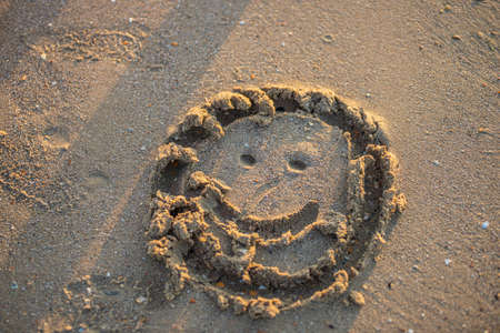 view on happy smiley face drawing on a sand.の写真素材