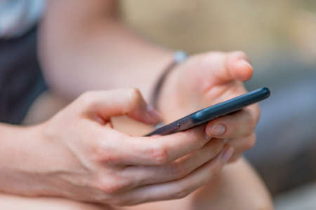 Close up of womens hands holding cell telephone, hipster girl watching video on mobile phone