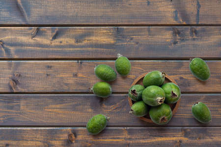 Green feijoa fruits in a cork plate on a dark wooden table. Tropical fruit feijoa. Set of ripe feijoa fruits. the view from the top. Copy space.の写真素材