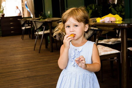Little blonde curly girl eat with relish macaronの写真素材
