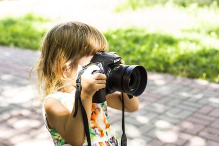 Closeup baby with a photo camera takes pictures outdoors.のeditorial素材