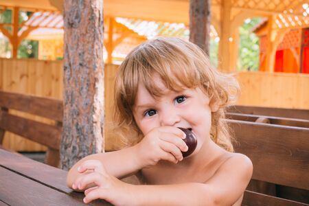 Curly blond girl eats a delicious plum outdoors. The concept of a healthy lifestyle, natural food, healthy nutrition. Fruit vitamins.の写真素材