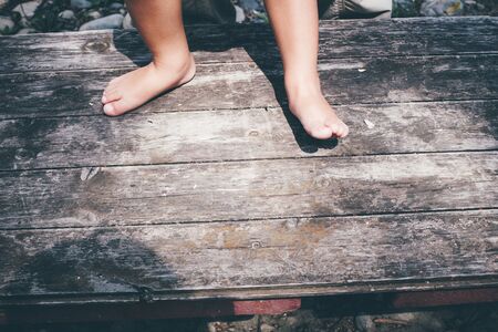 Little girl barefoot closeup of a foot on a plank background, playing outdoors in the countryside.の写真素材