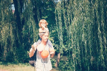 A little curly girl and her father are a close family. Children and people concept, father and child spending time outdoors.の写真素材