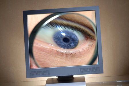 Eye with a magnifier in a monitor の写真素材