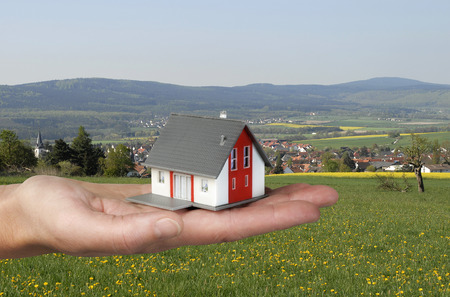 Hand holding an architectural model in front of a rural landscape の写真素材