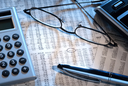 Marked stock price with glasses, calculator and pen の写真素材
