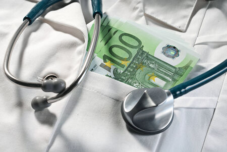 Stethoscope and money bills on a doctorの写真素材