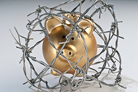 Golden piggy bank secured with barbed wireの写真素材