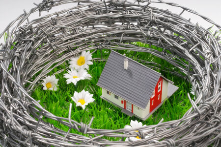 A house on a green field surrounded by barbed wire の写真素材
