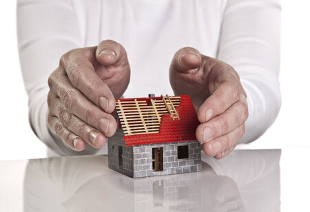 Hands close protectively around a new building の写真素材