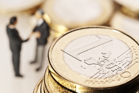 Euro coins and two businessmen in the backgroundの写真素材
