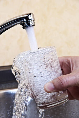 Water flowing from a tap into a glass の写真素材