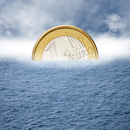 Euro coin sinks into the sea の写真素材