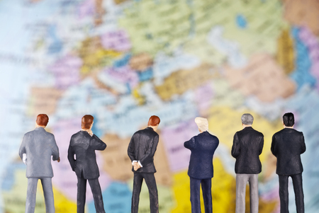 Businessmen as toy figures in front of a globe の写真素材