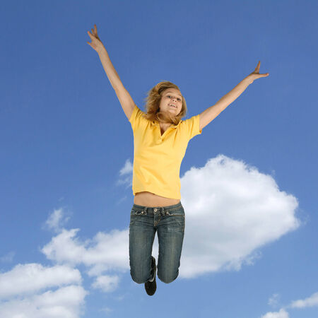 Blond teenager jumping in front of a blue sky の写真素材