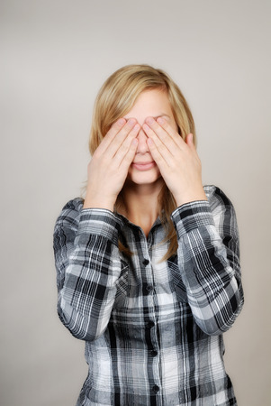 Young woman holding her hands over her eyes の写真素材