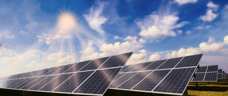 Photovoltaic system with solar modules and bright sun against a blue sky