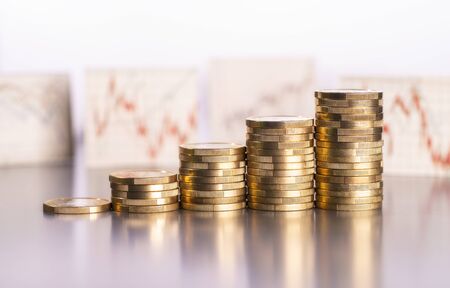 Rising stacks of coins and charts with stock prices in the backgroundの写真素材