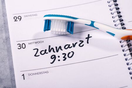 Calendar on which a toothbrush is placed and in which an appointment for a visit to the dentist is...