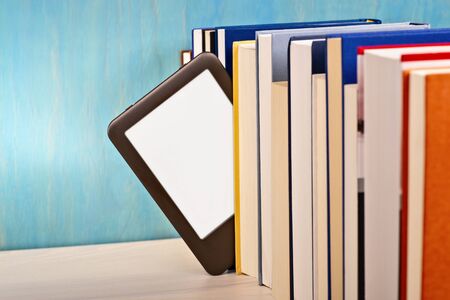 An e-book reader is inserted between a series of printed books