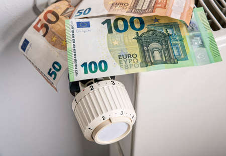 Radiator and thermostat with euro banknotes as a symbol for rising heating costsの写真素材