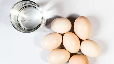 Eggs with glass of water isolated on white backgroundの写真素材