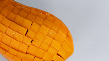 Mango slice cut to cubes close-up isolated on light grey backgroundの写真素材