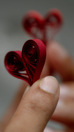 Red paper hearts in the hands of a girl on a gray backgroundの写真素材