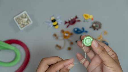 Close-up of a child's hand rolling a green paper stripes to make animal.の写真素材