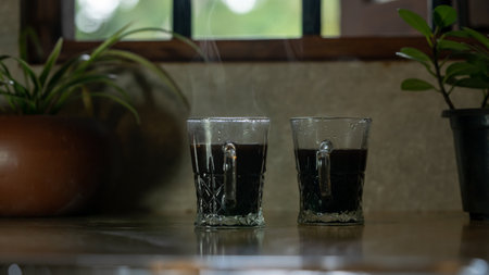 Two glasses of black coffee on a table in a cafe with plantsの写真素材