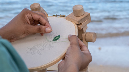 Close-up of a woman's hand knitting on a wooden wheel.