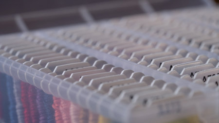 Close up of a white plastic box for a variety of floss threads wrapped bobbins.の写真素材