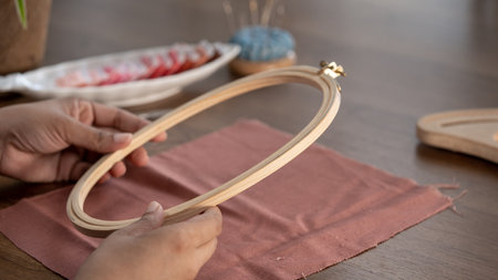 Close up of female hands making a embroidery project with frame or hoop on a wooden tableの写真素材