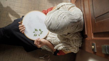 A young woman is knitting at home. embroidery needle and floss threadsの写真素材